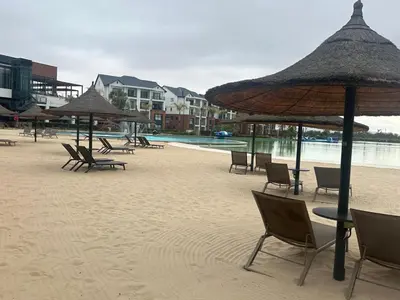 a beach with chairs and umbrellas on the sand at The Blyde Crystal Lagoon in Pretoria