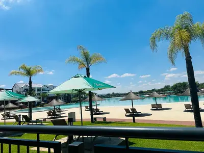 a beach with chairs and umbrellas and a swimming pool at The Blyde Crystal Lagoon in Pretoria