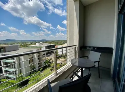 a balcony with a table and chairs and a window at Menlyn Maine Trilogy Apartment 611 in Pretoria