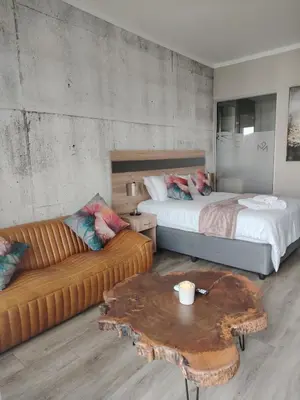 a bedroom with a bed and a couch and a table at Menlyn Maine Trilogy Apartment 611 in Pretoria