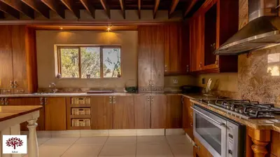 a kitchen with wooden cabinets and a stove top oven at Zebula Golf and Wildlife Estate - Porcupine Strolling Pax 8 - Moi Signature Luxury villa in Mabula