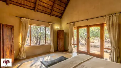 a bedroom with a bed and large windows at Zebula Golf and Wildlife Estate - Porcupine Strolling Pax 8 - Moi Signature Luxury villa in Mabula