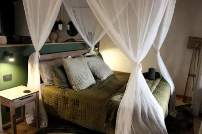 a bedroom with a canopy bed with curtains at Amare Cabin in the bush with all your needs! in Marloth Park