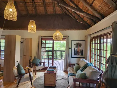 a living room with a couch and chairs and windows at Amare Cabin in the bush with all your needs! in Marloth Park