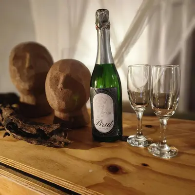 a bottle of wine and two glasses on a table at Amare Cabin in the bush with all your needs! in Marloth Park