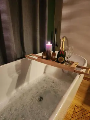a bath tub with a candle and bottles and glasses at Amare Cabin in the bush with all your needs! in Marloth Park