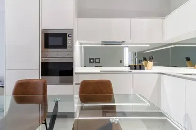 a white kitchen with two chairs and a glass table at #AlimamaSpaces: Jay's Cassini in Midrand