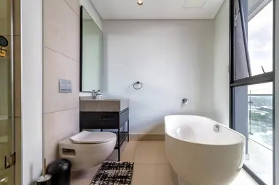 a bathroom with a tub and a toilet and a sink at #AlimamaSpaces: Jay's Cassini in Midrand