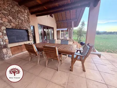 a wooden table and chairs on a patio with a tv at Zebula Golf and Wildlife Estate - Nights Sky Pax 16 - Moi Signature Luxury villa in Mabula