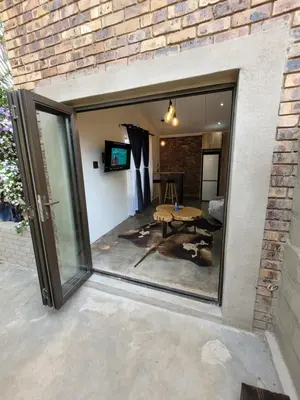 a large glass window in a brick wall with a patio at Nguni House in Mataffin