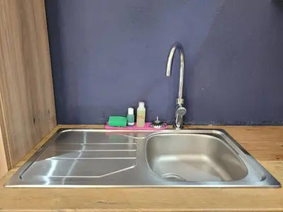 a stainless steel sink in a kitchen with a purple wall at Nguni House in Mataffin
