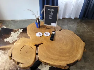a tree stump coffee table with a sign on it at Nguni House in Mataffin