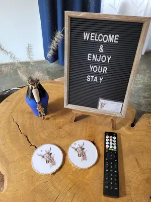 a welcome and enjoy your stay sign with two plates and a remote control at Nguni House in Mataffin