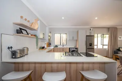 a kitchen with a white counter top and wooden cabinets at Utopia on the Rock2 in Nelspruit