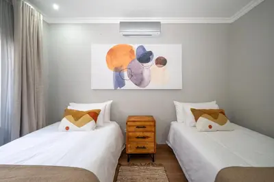 a bedroom with two beds and a painting on the wall at Utopia on the Rock2 in Nelspruit