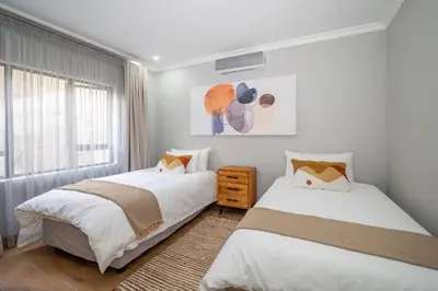 two beds in a bedroom with white walls and a window at Utopia on the Rock2 in Nelspruit