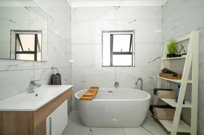 a white bathroom with a tub and a sink at Utopia on the Rock2 in Nelspruit