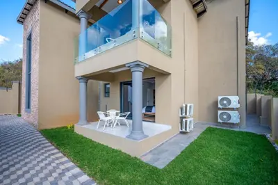 a house with a balcony with a lawn at Utopia on the Rock2 in Nelspruit