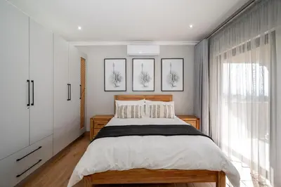 a bedroom with a large bed with white walls at Utopia on the Rock2 in Nelspruit