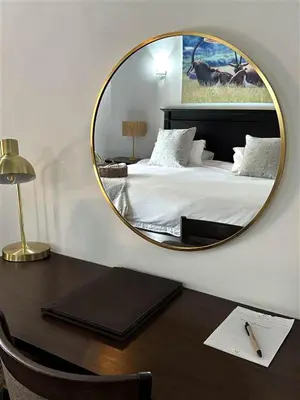 a bedroom with a bed with a mirror on a desk at Halali Wilderness Private Game Ranch in Hammanskraal
