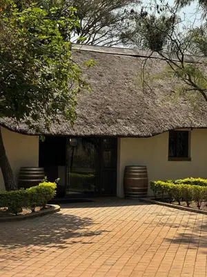 a building with a straw roof and a patio at Halali Wilderness Private Game Ranch in Hammanskraal