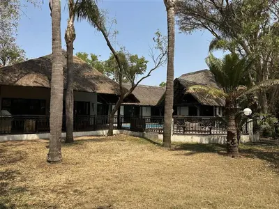 a house with palm trees in front of it at Halali Wilderness Private Game Ranch in Hammanskraal