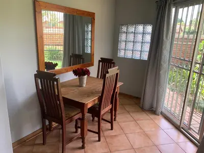 a dining room with a table and chairs and a mirror at Bougain Villa Guest House in Polokwane