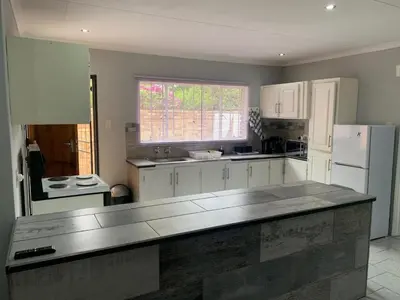 a kitchen with white cabinets and a large counter top at Bougain Villa Guest House in Polokwane