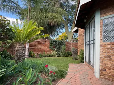 a brick house with a brick walkway next to a garden at Bougain Villa Guest House in Polokwane