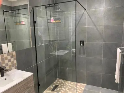 a shower with a glass door in a bathroom at Bougain Villa Guest House in Polokwane