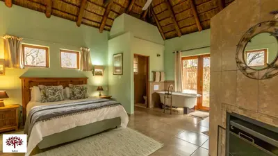 a bedroom with a bed and a tub and a fireplace at Zebula Golf and Wildlife Estate - Walk of the Eland Pax 12 - Moi Signature Luxury villa in Mabula