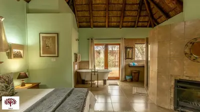 a bedroom with a bed and a bathroom with a tub at Zebula Golf and Wildlife Estate - Walk of the Eland Pax 12 - Moi Signature Luxury villa in Mabula