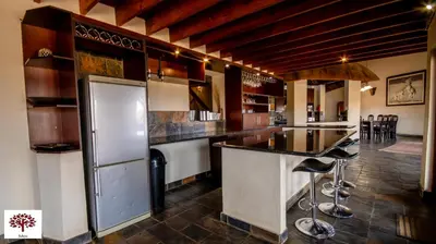 a kitchen with a bar with a refrigerator and stools at Zebula Golf and Wildlife Estate - Open Horizon Pax 8 - Moi Signature Luxury villa in Mabula