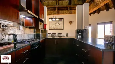 a kitchen with wooden cabinets and a counter top at Zebula Golf and Wildlife Estate - Open Horizon Pax 8 - Moi Signature Luxury villa in Mabula