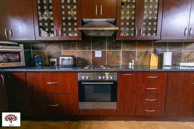 a kitchen with wooden cabinets and a stove top oven at Zebula Golf and Wildlife Estate - Aardwolf Pax 10 - Moi Signature Luxury villa in Mabula