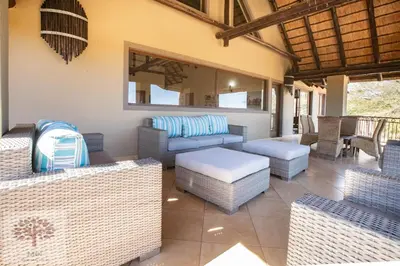 a patio with wicker chairs and a couch and tables at Zebula Golf and Wildlife Estate - Owl's Haven Pax 10 - Moi Signature Luxury villa in Mabula