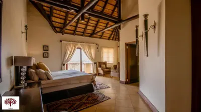 a bedroom with a bed and a living room at Zebula Golf and Wildlife Estate - Owl's Haven Pax 10 - Moi Signature Luxury villa in Mabula
