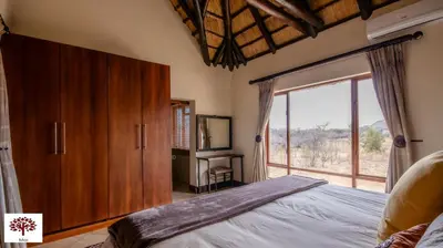 a bedroom with a bed and a large window at Zebula Golf and Wildlife Estate - Owl's Haven Pax 10 - Moi Signature Luxury villa in Mabula