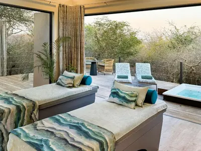 a patio with two beds and a tub on a deck at Radisson Safari Hotel Hoedspruit in Hoedspruit