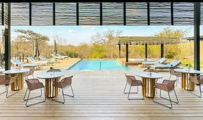 a patio with tables and chairs next to a pool at Radisson Safari Hotel Hoedspruit in Hoedspruit