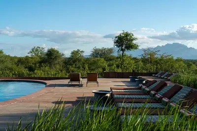 a patio with lounge chairs and a swimming pool at Radisson Safari Hotel Hoedspruit in Hoedspruit