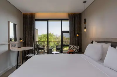 a bedroom with a large bed and a balcony at Radisson Safari Hotel Hoedspruit in Hoedspruit
