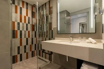 a bathroom with a sink and a shower with a mirror at Radisson Safari Hotel Hoedspruit in Hoedspruit