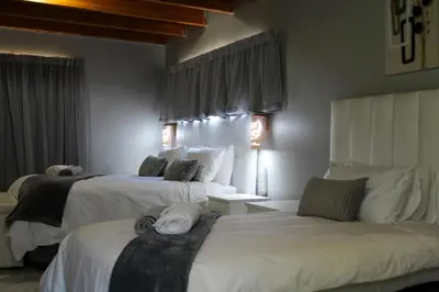 a hotel room with two beds with white sheets at Villa La Sola B&B and Self-Catering in Boksburg