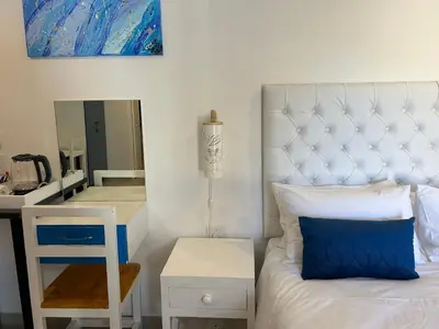 a bedroom with a bed and a desk and a mirror at Villa La Sola B&B and Self-Catering in Boksburg