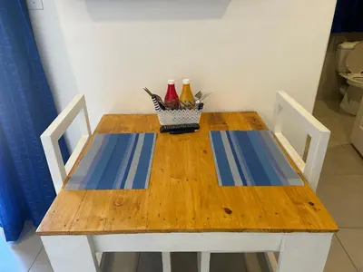 a wooden table with two chairs and bottles on it at Villa La Sola B&B and Self-Catering in Boksburg