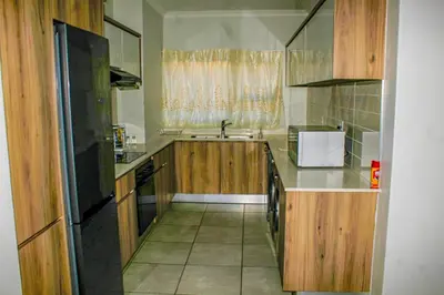 a kitchen with wooden cabinets and a sink at The Blyde Holiday beach in Pretoria