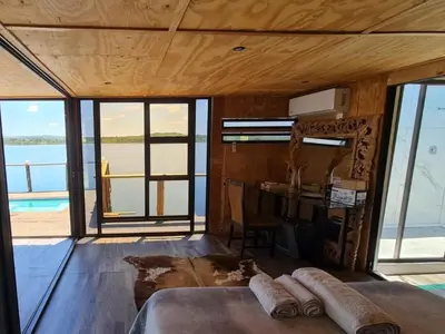 a room with a bed and a table and windows at Tshifaro Gardens in Thohoyandou
