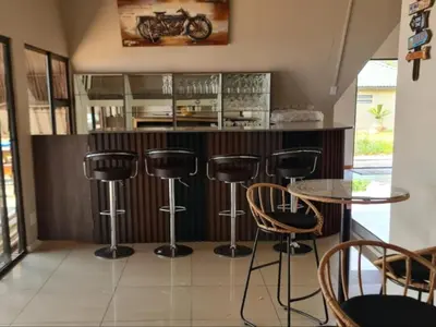 a kitchen with a bar with stools and a table at Tshifaro Gardens in Thohoyandou
