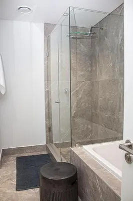 a bathroom with a shower and a stool next to a tub at Epic Getaway in Waterfall in Midrand